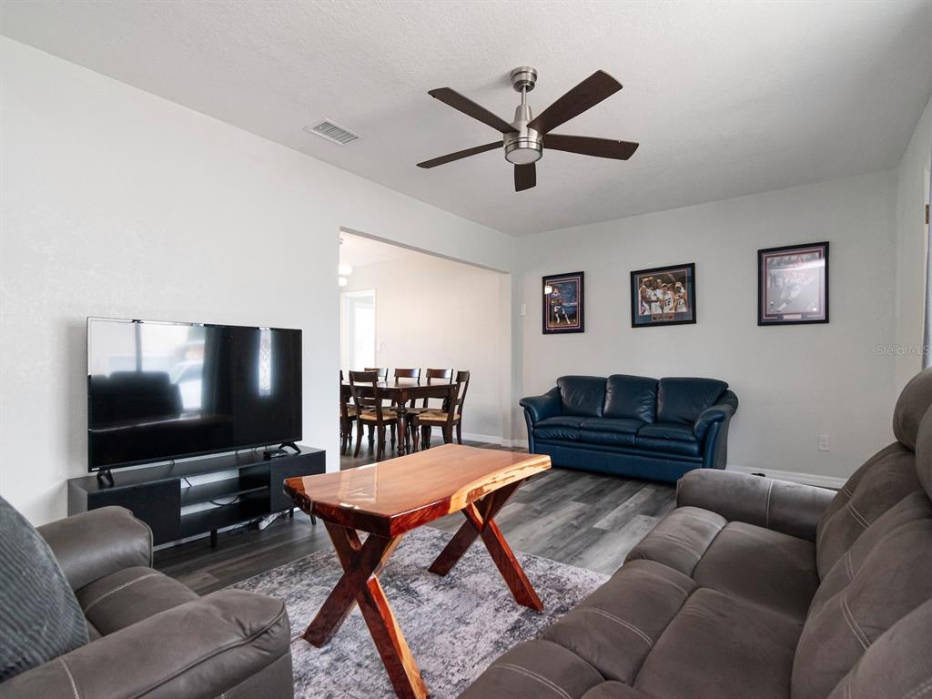 A living room features gray flooring, a live-edge coffee table, and a blue leather sofa — 5939 9TH AVENUE S, GULFPORT, FL