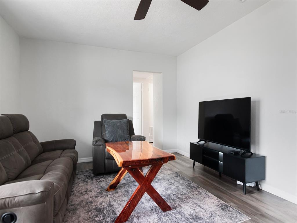 A living room features a gray sofa, a recliner, a live-edge coffee table, and television — 5939 9TH AVENUE S, GULFPORT, FL