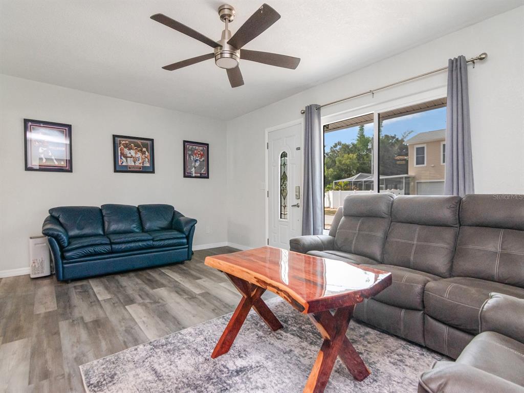 A living room features a blue sofa, a gray reclining sofa, and a live-edge coffee table — 5939 9TH AVENUE S, GULFPORT, FL