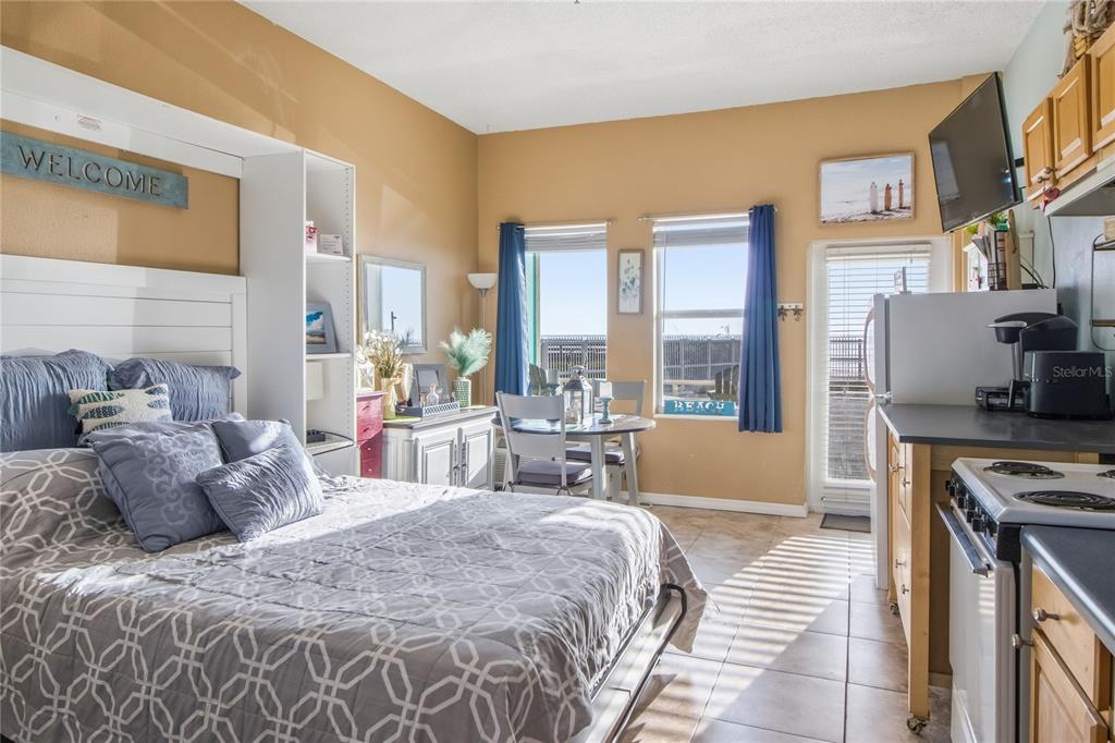 A studio apartment features a bed, a small dining table, and a kitchenette with tile flooring — 701 S ATLANTIC AVENUE UNIT 112, DAYTONA BEACH, FL