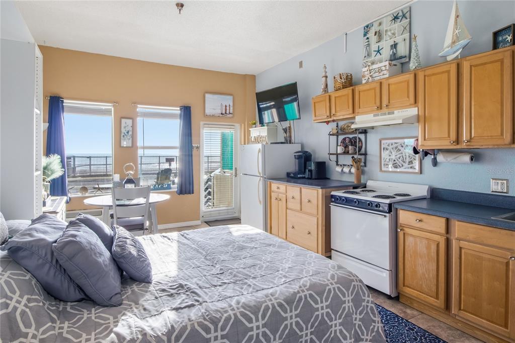 A studio apartment features a bed, kitchenette with wooden cabinets, and a view of the ocean — 701 S ATLANTIC AVENUE UNIT 112, DAYTONA BEACH, FL