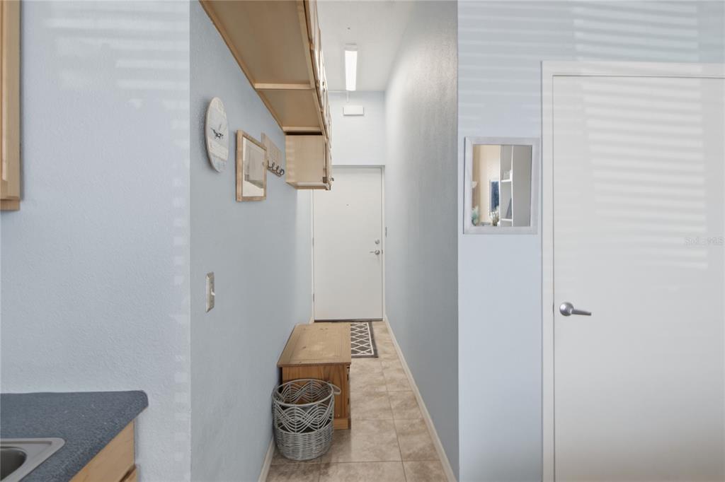A narrow hallway features light blue walls, tile flooring, a wooden bench, and a white door — 701 S ATLANTIC AVENUE UNIT 112, DAYTONA BEACH, FL