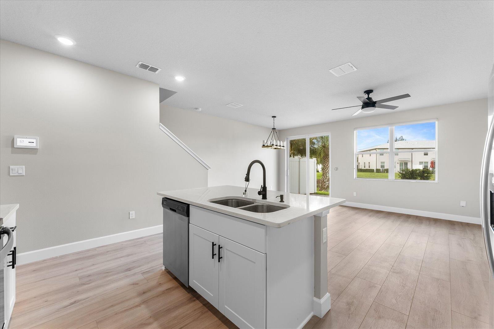 A kitchen island with a sink and dishwasher sits in an open-concept living area — 5661 Mentmore Drive, Mangonia Park FL 33407, MANGONIA PARK, FL