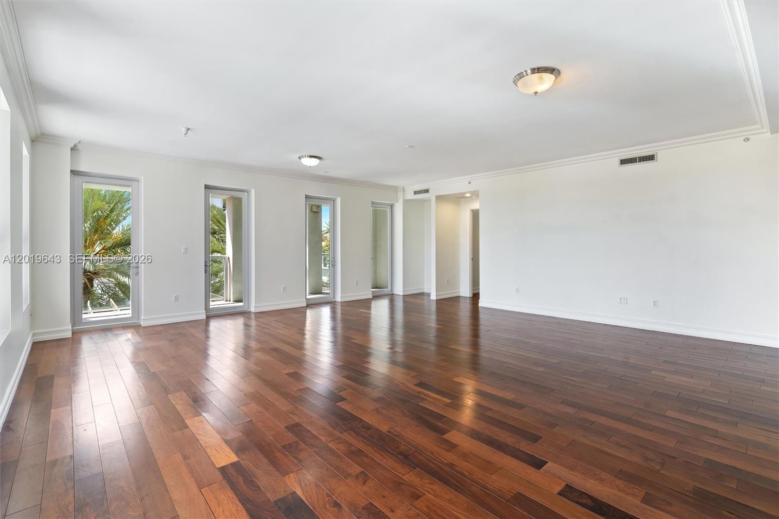 An empty room features dark hardwood floors, white walls, and multiple glass balcony doors — 455 E Palmetto Park Rd # 3, Boca Raton FL 33432, BOCA RATON, FL