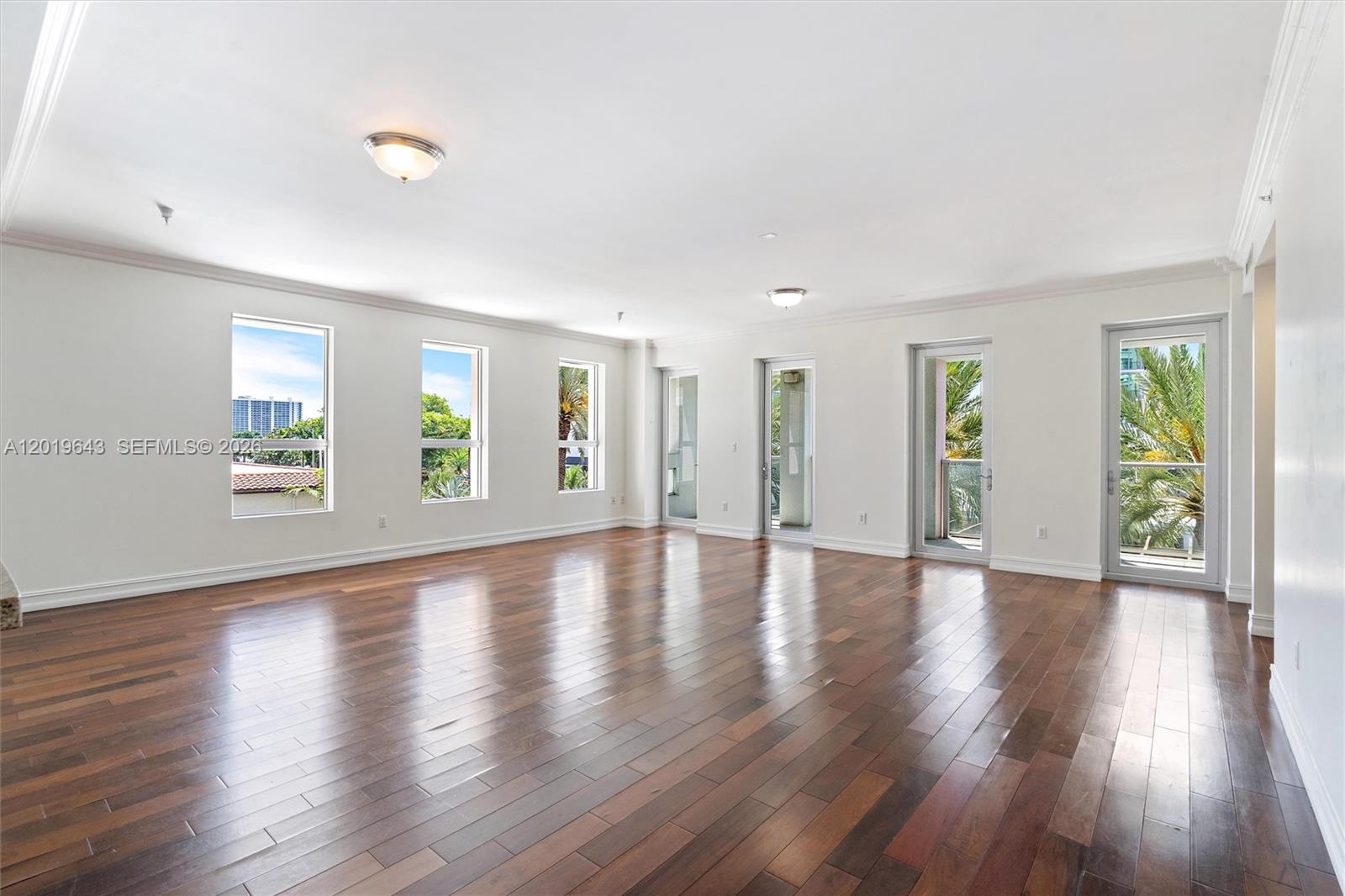An empty room features dark hardwood floors, white walls, and multiple windows and glass doors — 455 E Palmetto Park Rd # 3, Boca Raton FL 33432, BOCA RATON, FL