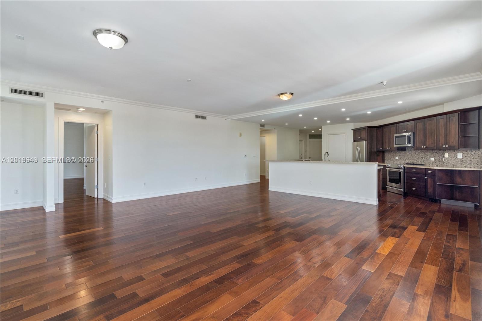 An open-concept living area features dark hardwood floors and a kitchen with dark wood cabinetry — 455 E Palmetto Park Rd # 3, Boca Raton FL 33432, BOCA RATON, FL