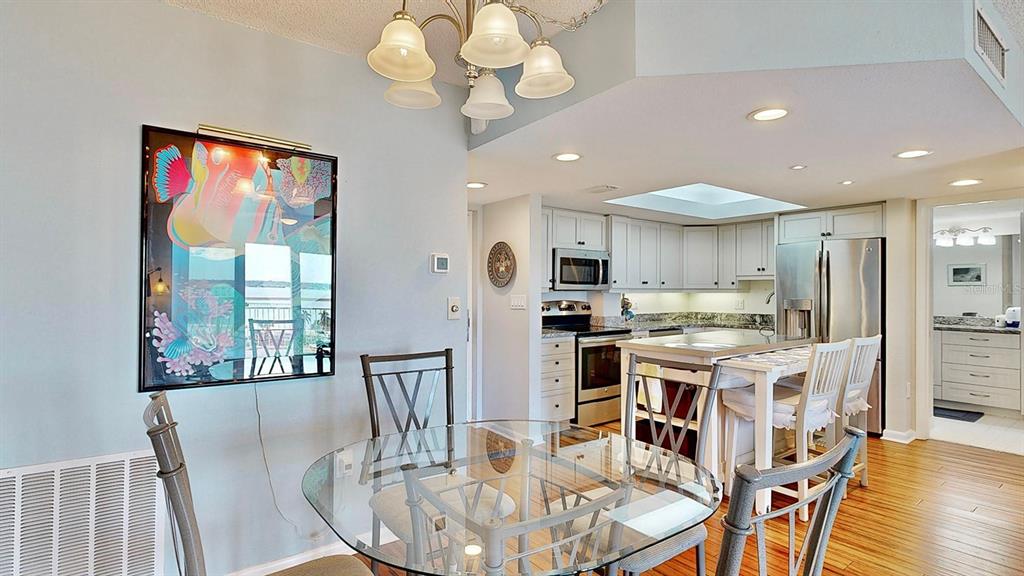 A dining area with a glass table and chandelier opens to a kitchen with stainless appliances — 4900 BRITTANY DRIVE S UNIT 1011, ST PETERSBURG, FL