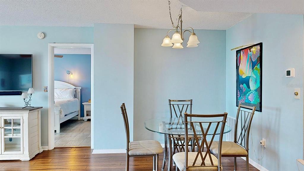 A dining area with a glass table and chairs sits adjacent to a bedroom doorway — 4900 BRITTANY DRIVE S UNIT 1011, ST PETERSBURG, FL