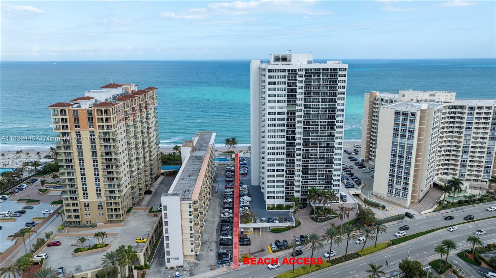 An aerial view shows three high-rise residential buildings near the ocean with a parking lot — 3135 S Ocean Dr # 230, Hallandale Beach FL 33009, HALLANDALE BEACH, FL