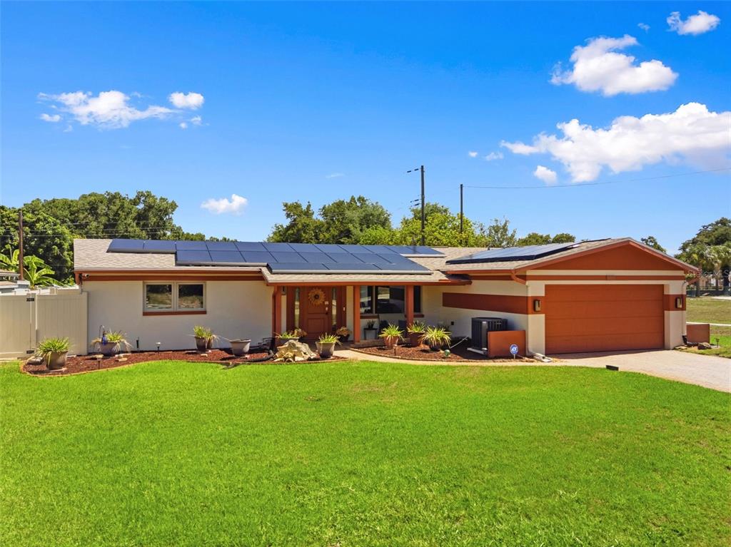 A single-story house with a solar panel roof, a two-car garage, and a front lawn — 5915 46TH AVENUE N, KENNETH CITY, FL