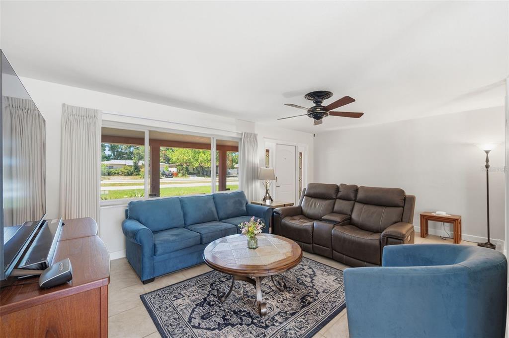 A living room features a blue sofa, a brown leather loveseat, and a round coffee table — 5915 46TH AVENUE N, KENNETH CITY, FL