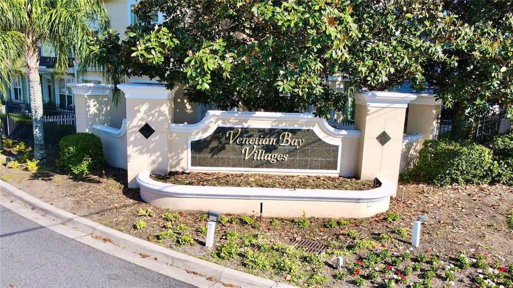 A stone monument sign for Venetian Bay Villages stands in front of a residential building — 4005 SAN SEBASTIAN DRIVE UNIT 107, KISSIMMEE, FL