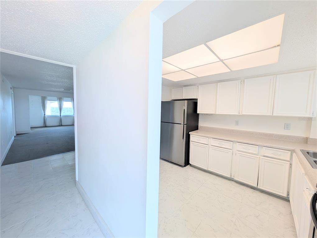 A kitchen with white cabinets and stainless steel appliances opens into a carpeted living area — 4129 LAKE BAYSHORE DRIVE UNIT C-501, BRADENTON, FL