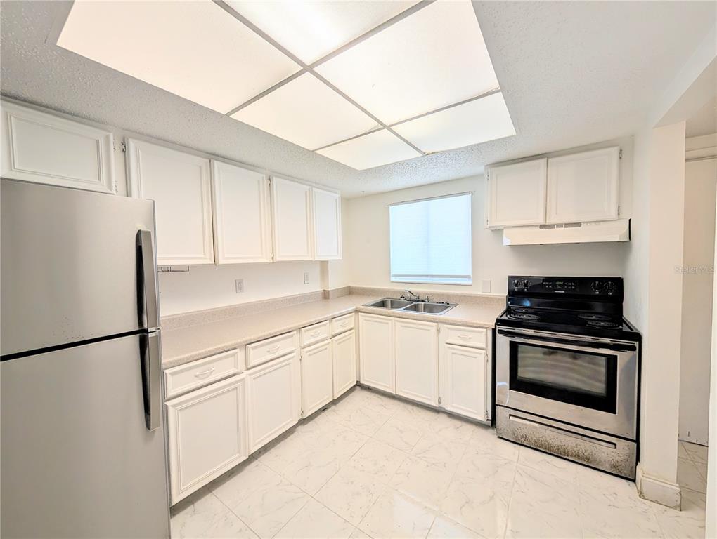 A kitchen features white cabinets, stainless steel appliances, a double sink, and tiled flooring — 4129 LAKE BAYSHORE DRIVE UNIT C-501, BRADENTON, FL