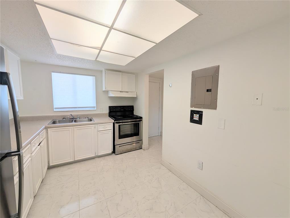 A kitchen features white cabinets, stainless steel appliances, and light-colored tile flooring — 4129 LAKE BAYSHORE DRIVE UNIT C-501, BRADENTON, FL