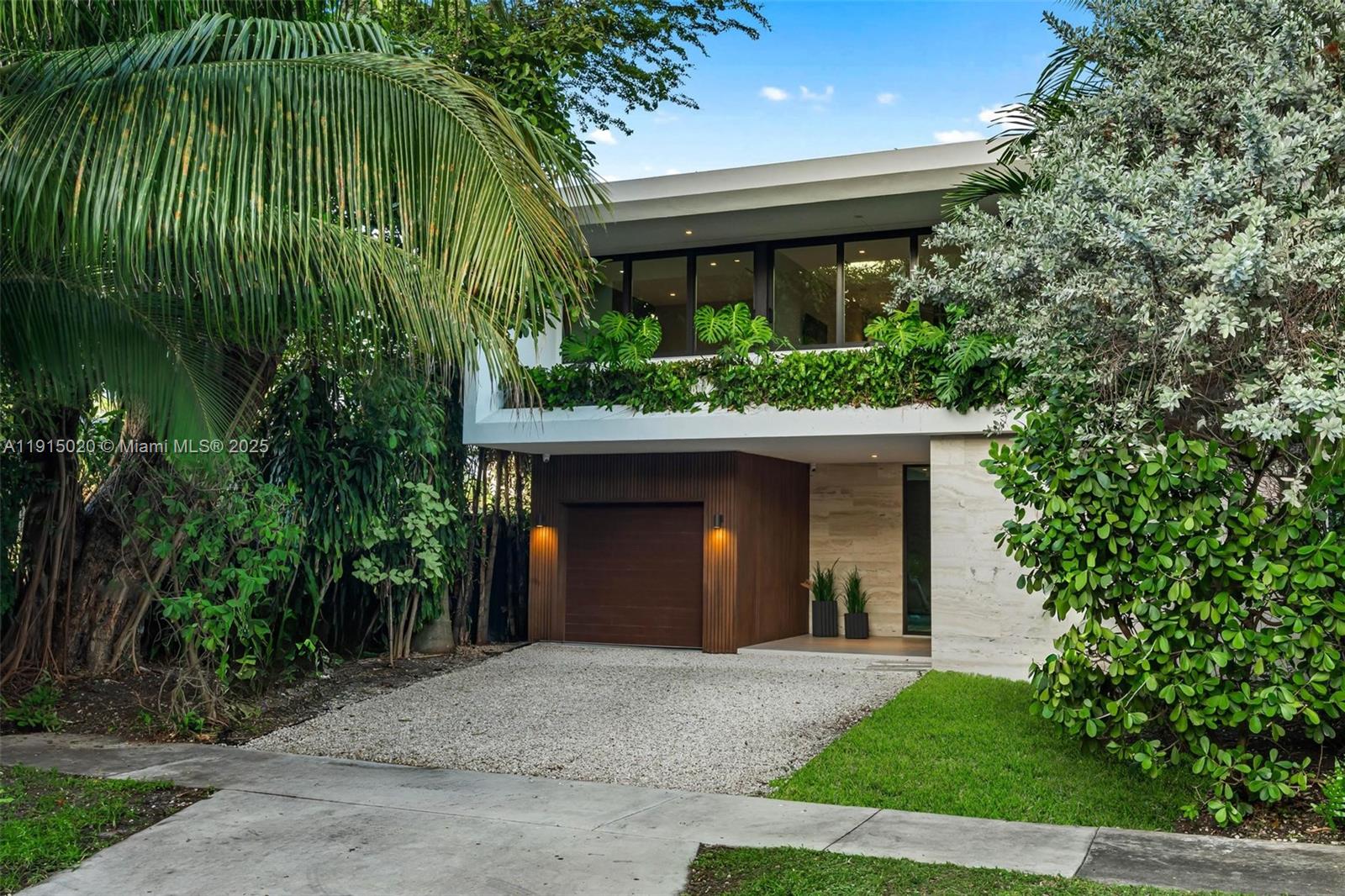 A modern two-story house features a wood-paneled garage, stone facade, and lush balcony landscaping — 77 SW 18th Terrace, Miami FL 33129, MIAMI, FL