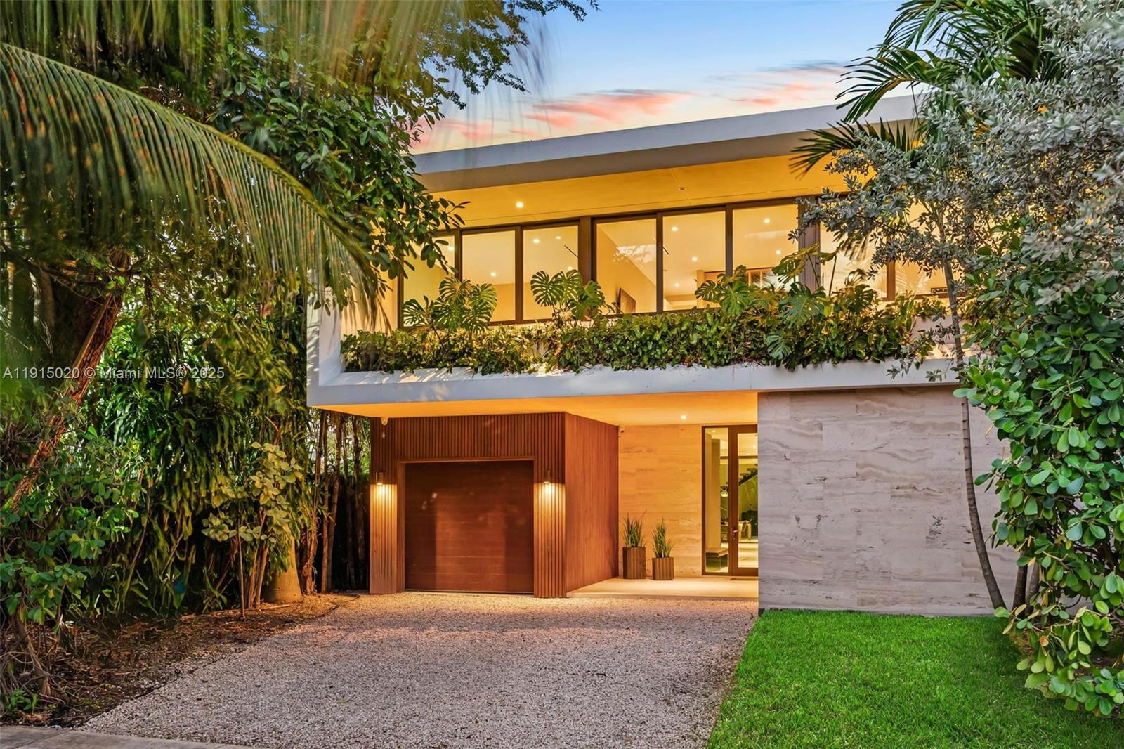 A modern two-story house features a wood-paneled garage, stone facade, and lush tropical landscaping — 77 SW 18th Terrace, Miami FL 33129, MIAMI, FL