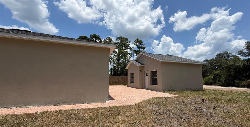 The exterior view shows two tan stucco buildings connected by a paved brick patio area — 1214 7TH AVENUE, DELAND, FL