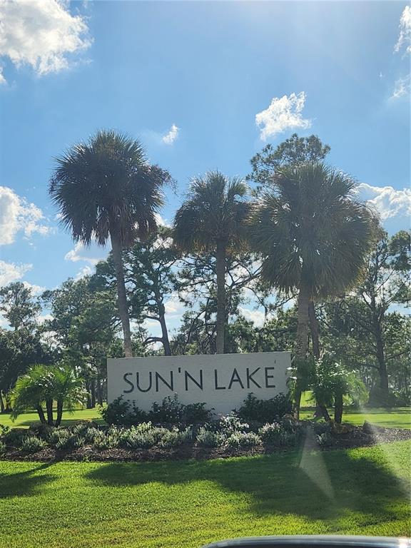 A concrete sign reading SUN'N LAKE stands in a grassy area with palm trees behind it — 5101 SAN JUAN DRIVE, SEBRING, FL