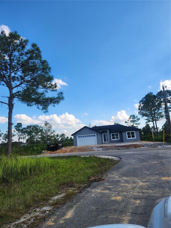 A newly constructed gray single-story house with a white garage door sits on a lot — 5101 SAN JUAN DRIVE, SEBRING, FL