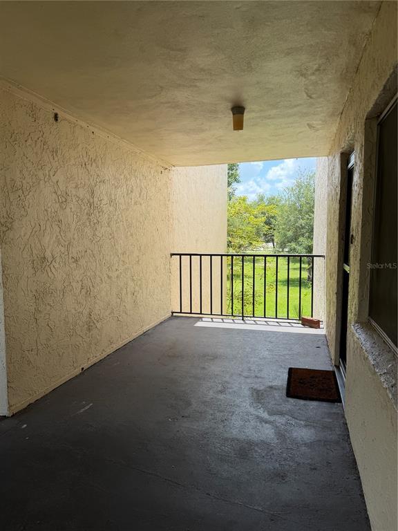 A covered balcony with a concrete floor, stucco walls, and a black metal railing — 1130 N LAKE PARKER AVENUE UNIT C229, LAKELAND, FL