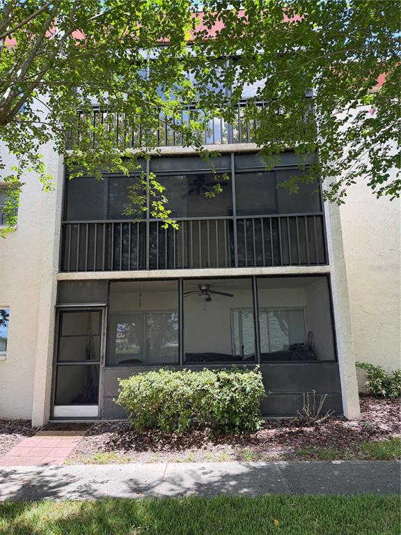 A three-story building exterior features stacked screened-in porches with a ground-level entry door — 1130 N LAKE PARKER AVENUE UNIT C229, LAKELAND, FL
