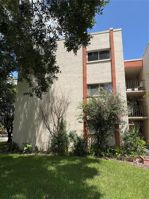 A three-story apartment building exterior with beige stucco walls and reddish-brown vertical accents — 1130 N LAKE PARKER AVENUE UNIT C229, LAKELAND, FL