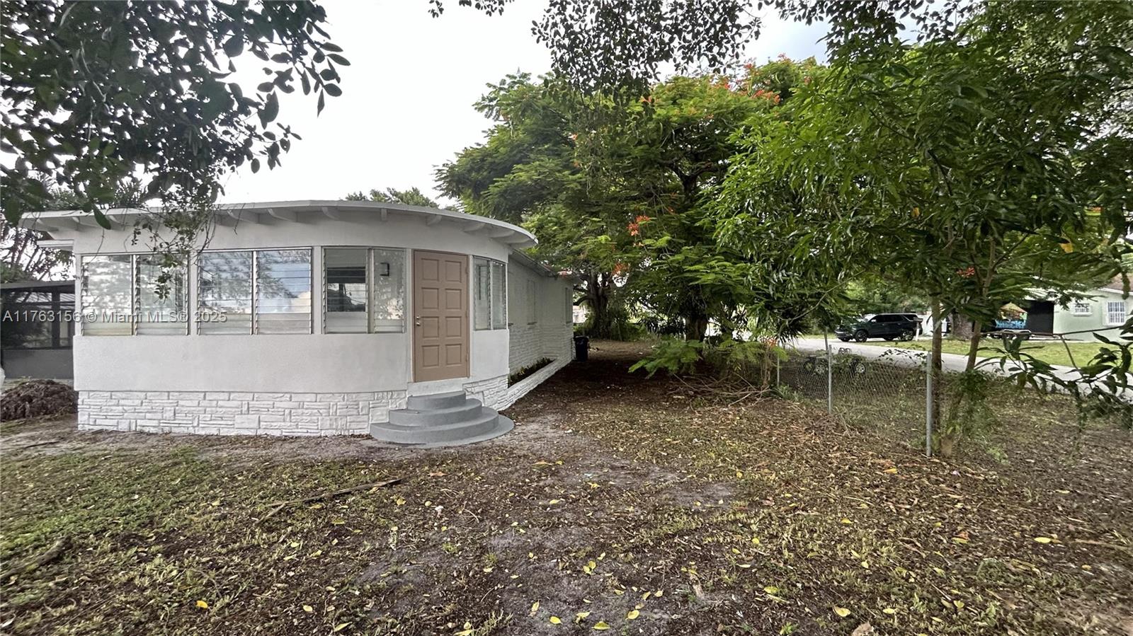 A white house with a curved front wall, large windows, and a tan door — 205 Seaman Ave, Opa-Locka FL 33054, OPA-LOCKA, FL