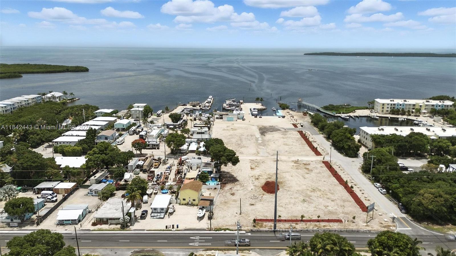 An aerial view shows a coastal property with a large vacant lot and boat docks — 97601 Overseas Hwy, Key Largo FL 33037, KEY LARGO, FL