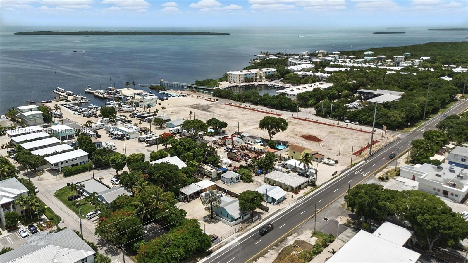 An aerial view shows a coastal property with a large vacant lot and nearby buildings — 97601 Overseas Hwy, Key Largo FL 33037, KEY LARGO, FL