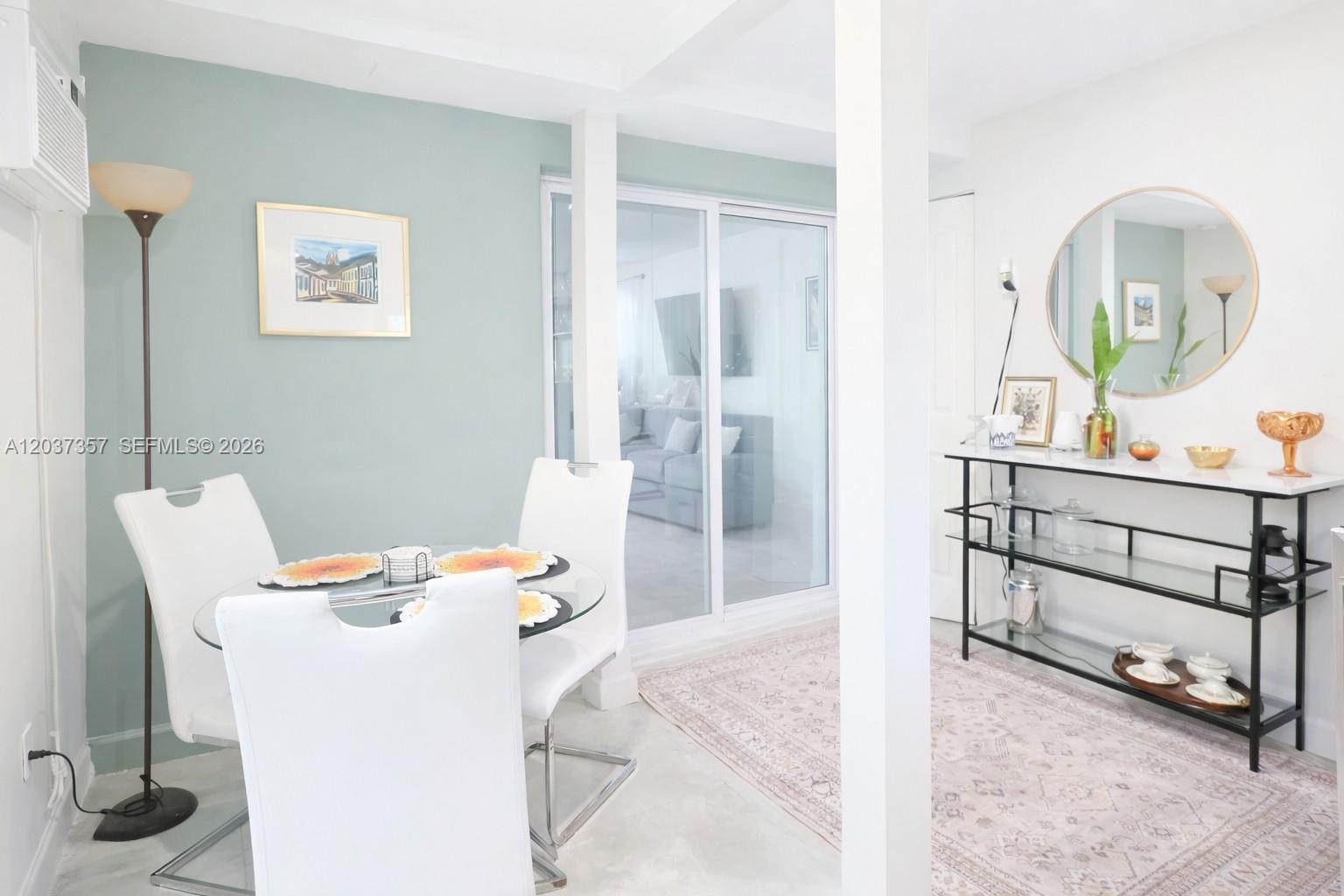 A dining area features a glass table, white chairs, and a console table with decor — FORT LAUDERDALE, FL