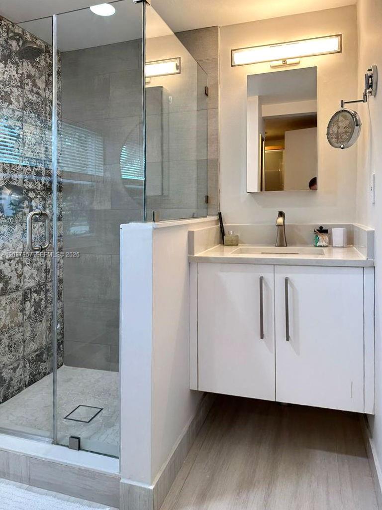 A bathroom features a glass-enclosed walk-in shower with patterned tile and a white vanity — FORT LAUDERDALE, FL