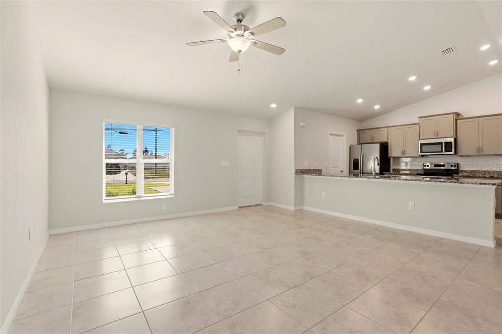 An open-concept living area features light tile flooring, a ceiling fan, and an adjacent kitchen — 3600 NE 20TH PLACE, CAPE CORAL, FL