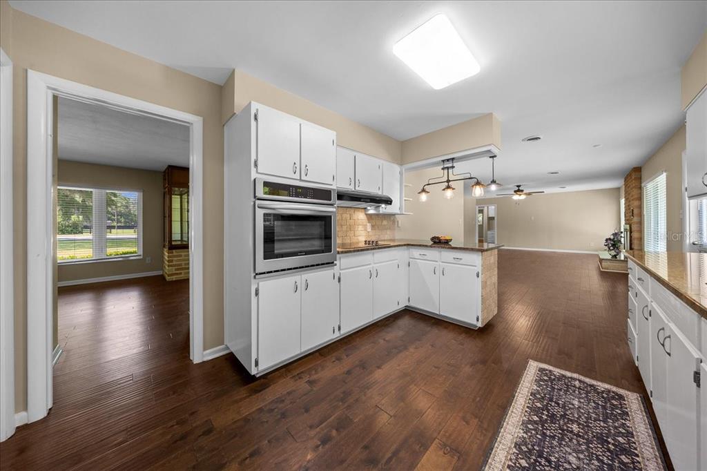 A kitchen with white cabinets, a built-in oven, and dark wood flooring — 2333 E FORT KING STREET, OCALA, FL