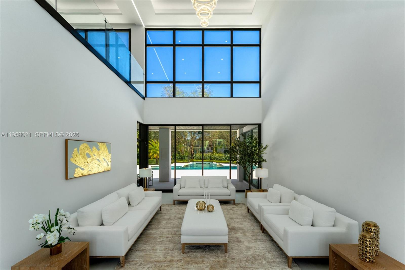 A bright living room features high ceilings, floor-to-ceiling windows, white furniture, and a pool view — 9525 SW 95th Ct, Miami FL 33176, MIAMI, FL