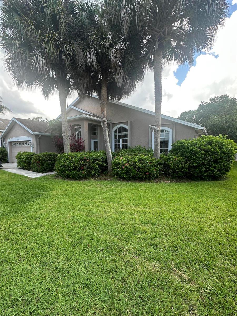 A single-story house with a tan exterior, arched windows, and palm trees in the front yard — 3102 NW Windemere Drive, Jensen Beach FL 34957, JENSEN BEACH, FL