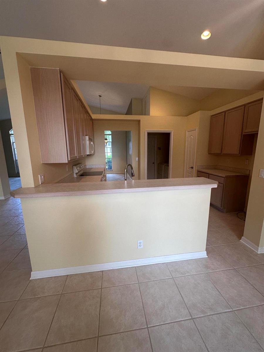 A kitchen features light-colored cabinets, a breakfast bar, and tile flooring — 3102 NW Windemere Drive, Jensen Beach FL 34957, JENSEN BEACH, FL