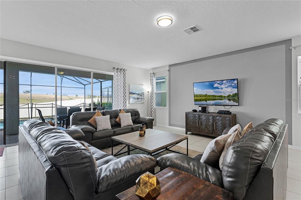 A living room features two dark leather sofas, a wooden coffee table, and a television — 1754 CARIBBEAN VIEW TERRACE, KISSIMMEE, FL