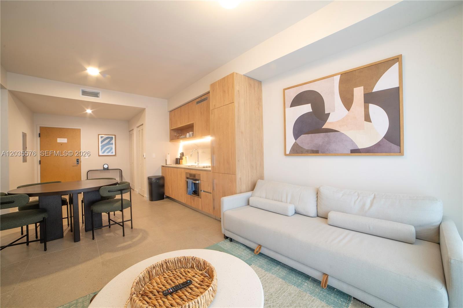 A modern studio apartment features a kitchenette, dining area, and a light-colored sofa — 11 NE 6TH # 1403, Miami FL 33132, MIAMI, FL