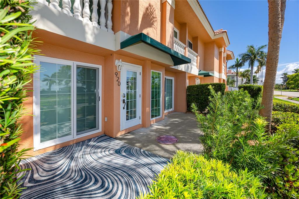 The exterior of a peach-colored building features a patio with a patterned rug and landscaping — 920 NORTH SHORE DRIVE NE, ST PETERSBURG, FL