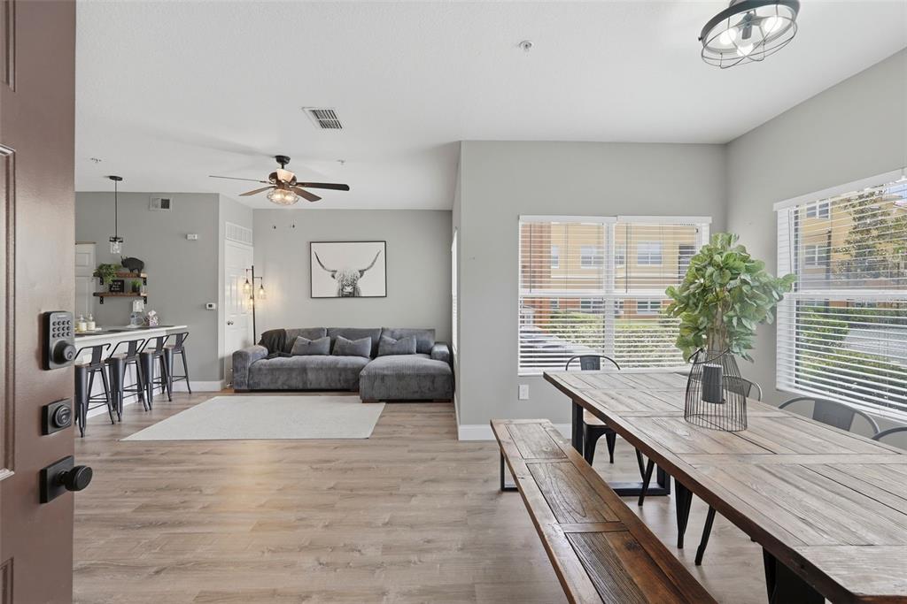 An open-concept living and dining area features wood-look flooring, a gray sectional, and a table — 10764 70TH AVENUE UNIT 6104, SEMINOLE, FL