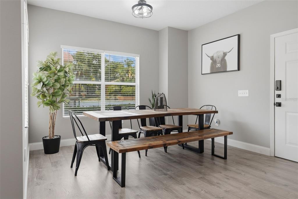 A dining room features a wooden table with a bench, metal chairs, and gray flooring — 10764 70TH AVENUE UNIT 6104, SEMINOLE, FL
