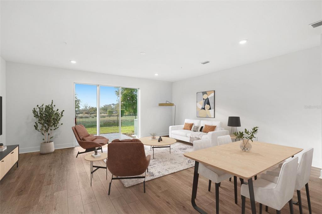 A bright, open-concept living and dining area features wood-look flooring, a sliding glass door, and modern furniture — 1125 ORANGE TRAILSIDE WAY, OCOEE, FL