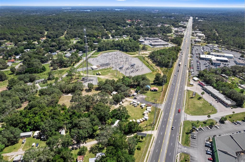 An aerial view shows a power substation, a tall communications tower, and a multi-lane highway — 3865-3899 E GULF TO LAKE HIGHWAY, INVERNESS, FL