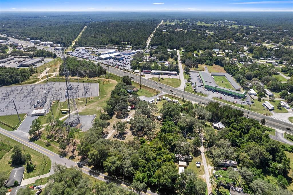 An aerial view shows a power substation, a highway, and surrounding wooded residential and commercial areas — 3865-3899 E GULF TO LAKE HIGHWAY, INVERNESS, FL