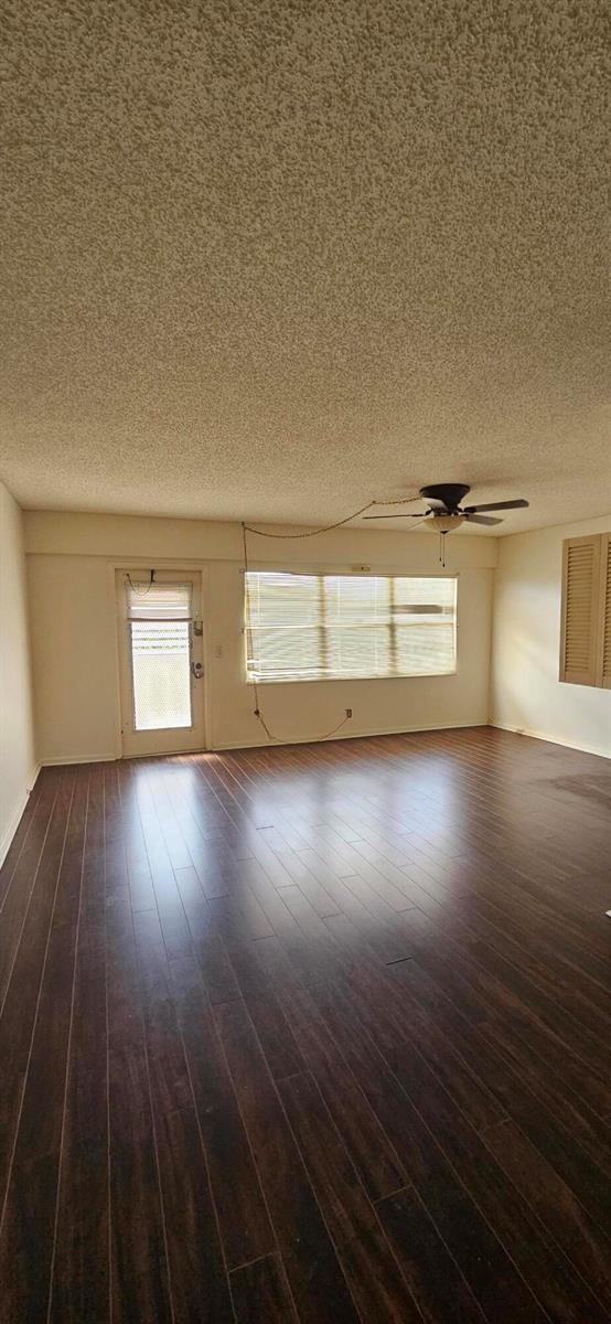 An empty living room features dark wood-look flooring, a popcorn ceiling, and a ceiling fan — 198 E Preston Way # 198, Boca Raton FL 33434, BOCA RATON, FL