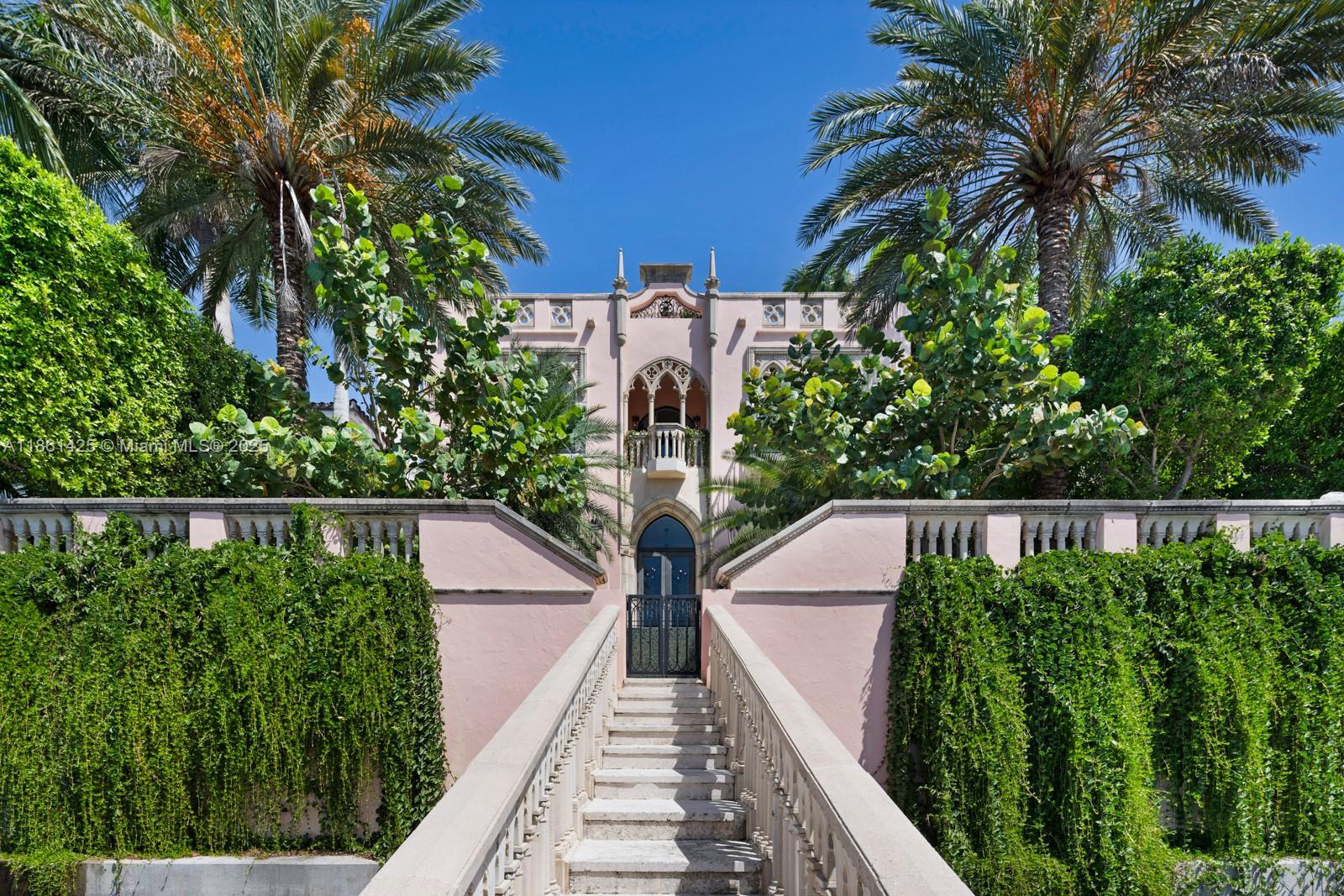 A pink Mediterranean-style mansion features a grand stone staircase leading to an arched entryway — 1840 S Bayshore Ln, Miami FL 33133, MIAMI, FL