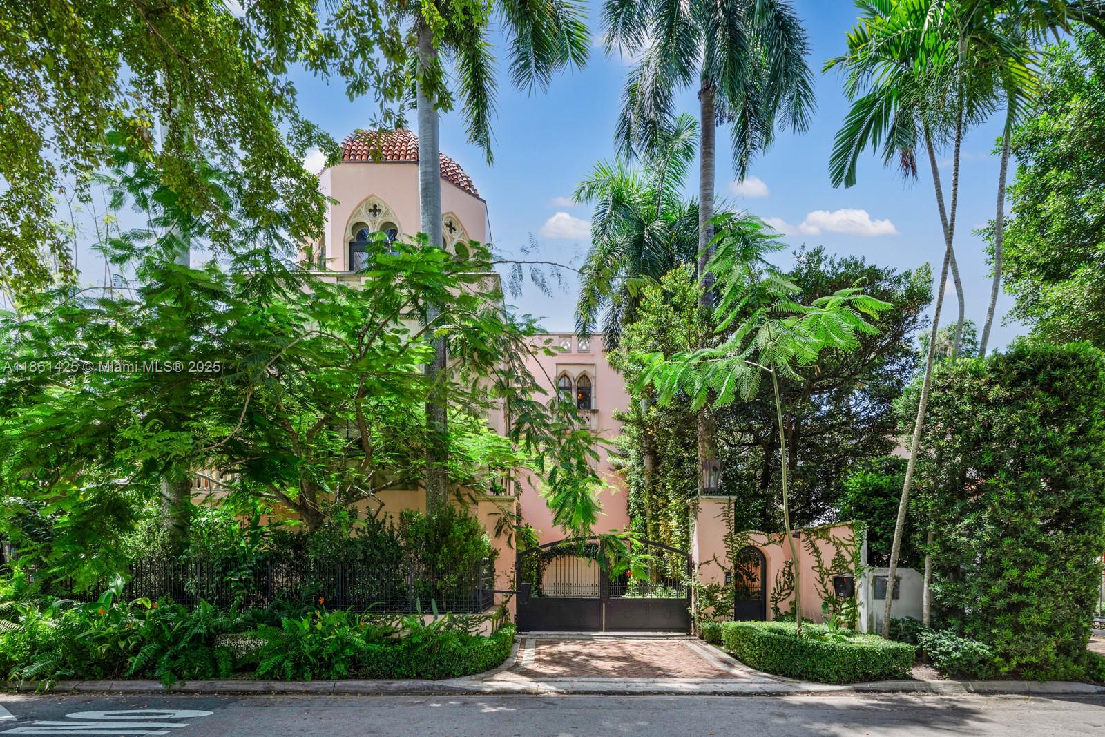 A pink Mediterranean-style house with a domed tower is viewed from behind a gated entrance — 1840 S Bayshore Ln, Miami FL 33133, MIAMI, FL