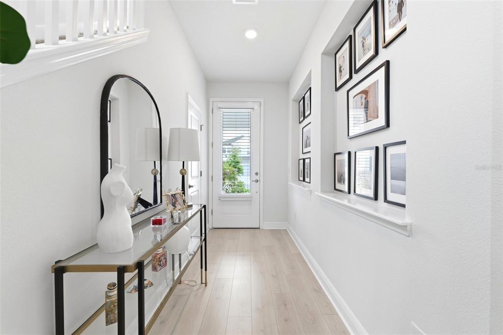 A bright entryway features a glass console table, a large arched mirror, and a gallery wall — 28905 ORANGE BERRY DRIVE, WESLEY CHAPEL, FL