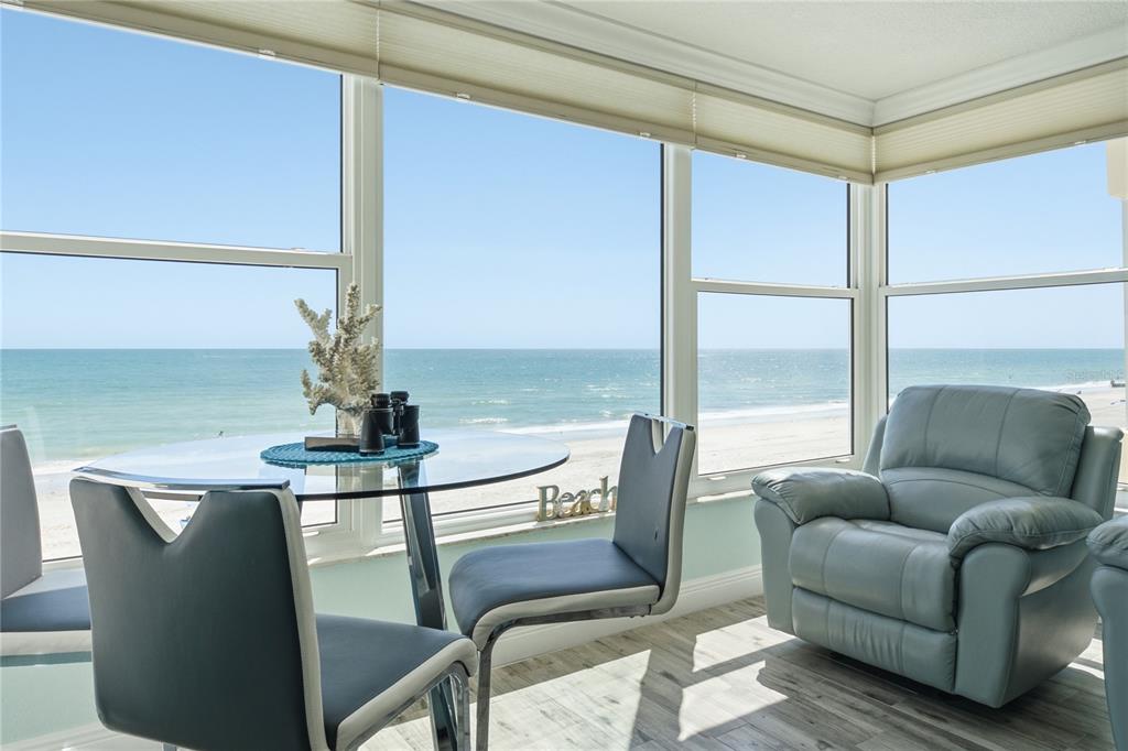 A sunroom features a glass dining table, two chairs, and a recliner overlooking the beach — 14800 GULF BOULEVARD UNIT 303, MADEIRA BEACH, FL